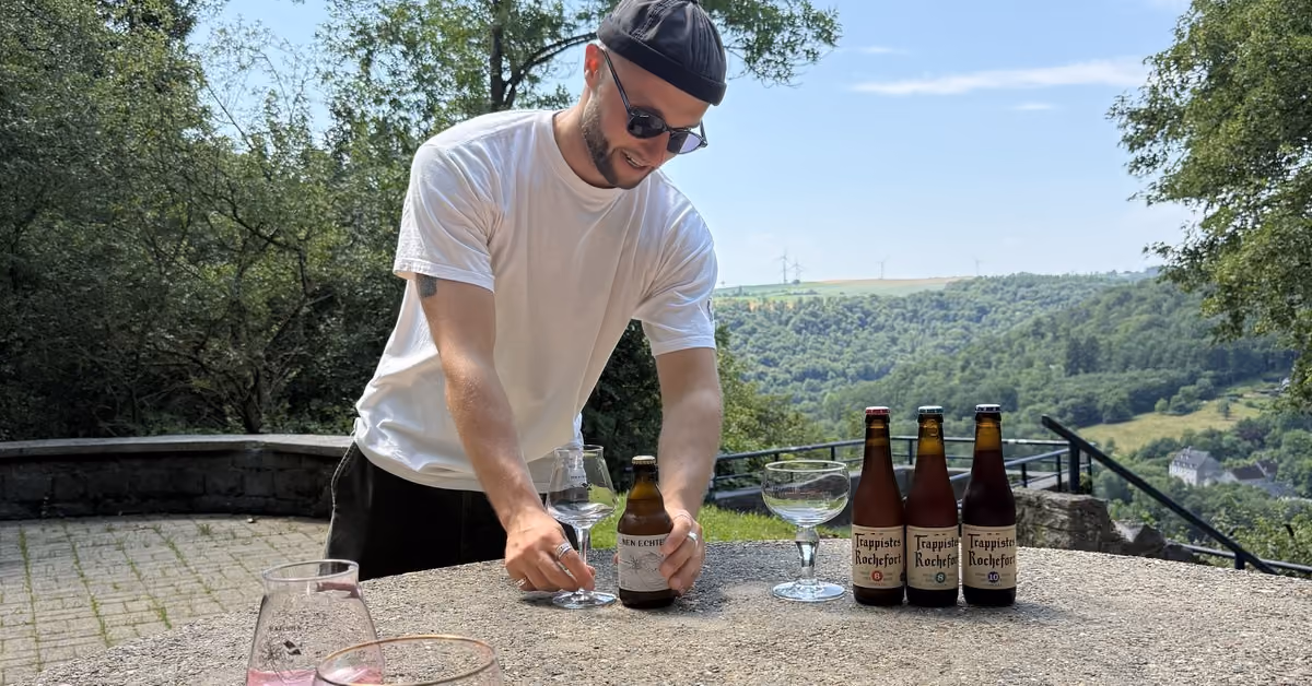 Joris setting out bottles of Rochefort 6, 8 and 10 and a bottle of Nen Echten set out on a stone table above a green valley